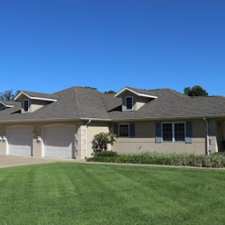 A modern single-family home with a well-maintained lawn under a clear blue sky.