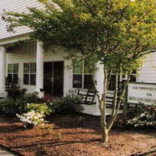 A well-maintained house exterior with a porch, bench, and landscaped garden.