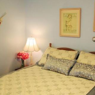 A cozy bedroom with a neatly made bed, decorative pillows, a bedside lamp, and wall art.