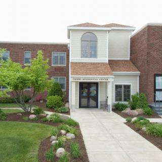 A welcoming front entrance of a residential building surrounded by lush landscaping.