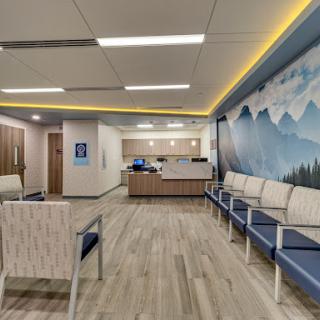 A modern and inviting hospital waiting room with comfortable seating and a calming mural.
