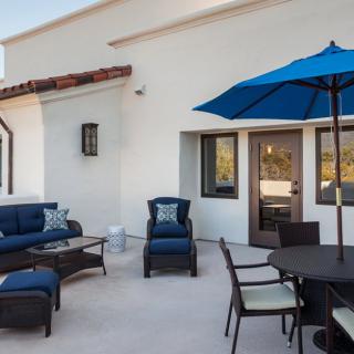 A modern patio with comfortable outdoor seating, a blue umbrella, and stylish furniture.