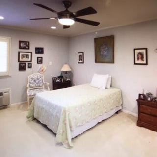 A cozy bedroom with a single bed, ceiling fan, and decorated walls.