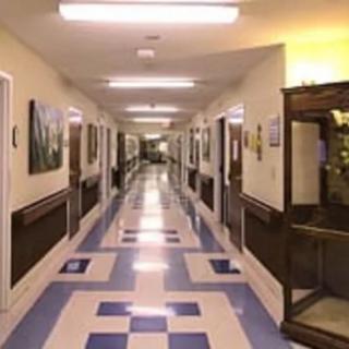 A well-lit hallway with tiled flooring and doors on both sides.
