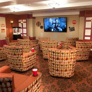 A cozy home theater setup with patterned chairs facing a large television.
