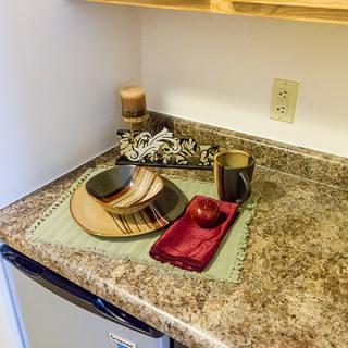 A kitchen counter with decorative dishes, an apple, and candles.