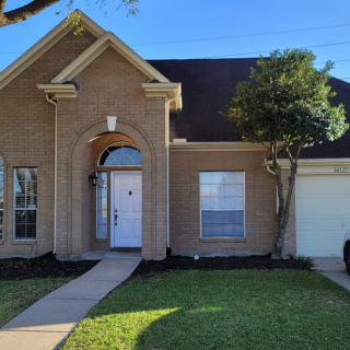 A suburban brick house with a well-maintained front yard.
