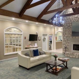 A modern living room featuring a stone fireplace, wooden beams, and elegant furnishings.
