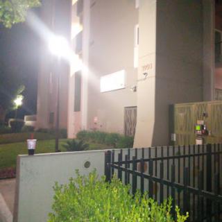 A nighttime view of a building with bright lights and a fenced area.