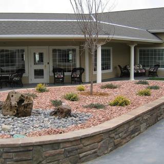 A landscaped garden with rocks and plants in front of a building patio.