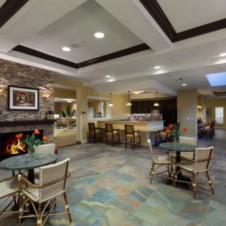 A cozy and modern lobby with a fireplace, seating area, and tables.