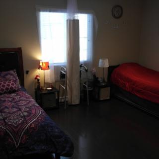 A cozy bedroom with two beds and dim lighting from lamps.