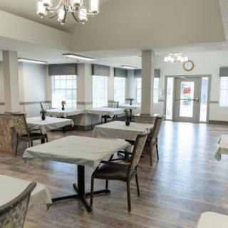 A modern and spacious dining area featuring elegantly arranged tables and chairs, illuminated by natural light.