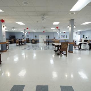 An empty dining area with tables and chairs arranged neatly, featuring a bright and spacious layout.