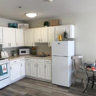 A modern kitchen with white cabinets, appliances, and a small dining area.