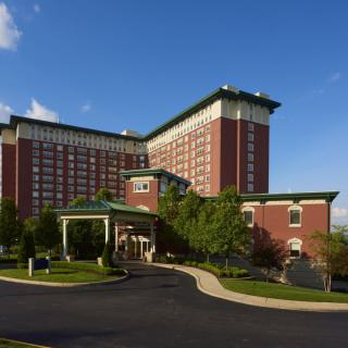 A large hotel building with a brick facade and green rooftops under a clear blue sky.