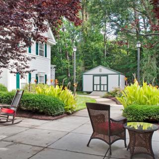 A tranquil backyard patio with outdoor furniture and lush greenery.