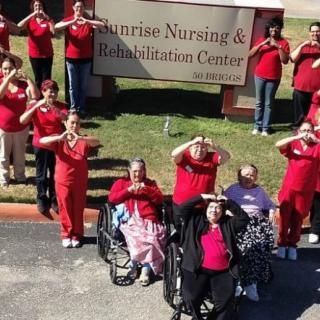 Healthcare workers and residents gather for a group photo outside the Sunrise Nursing & Rehabilitation Center.