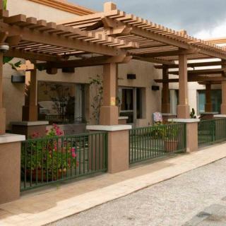 A modern building with wooden pergolas and a fenced patio area.
