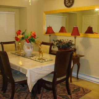 A cozy dining room with a table set, adorned with flowers and warm lighting.