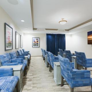 A modern waiting room featuring blue upholstered chairs and decorative artwork on the walls.