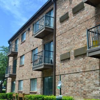 A brick apartment building with multiple balconies under a clear blue sky.