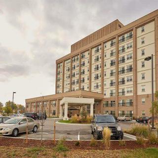 A large hotel building with a parking lot in front under a cloudy sky.