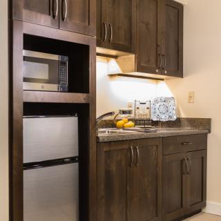 A compact kitchenette featuring a microwave, fridge, and wooden cabinets.