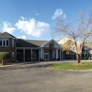 A large building with a welcoming entrance and surrounding trees under a cloudy sky.