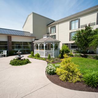 A well-maintained garden area with a gazebo and fountain in front of a modern building.