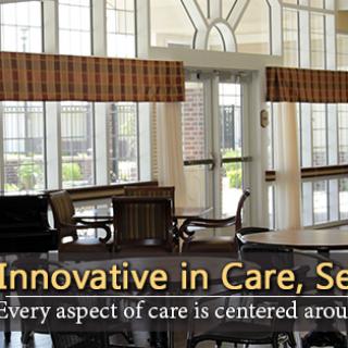 A cozy interior of a care facility featuring large windows and comfortable seating.