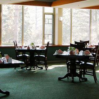 A sunlit dining area with several tables and chairs arranged neatly.
