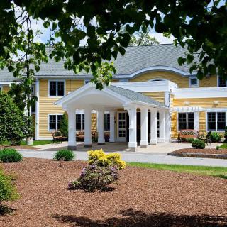 A large, yellow house with white columns and manicured landscaping.