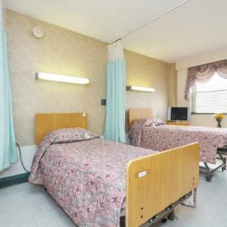 A hospital room with two patient beds and privacy curtains.