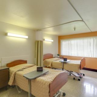 A clean and bright hospital room with two patient beds.