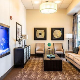 A modern and cozy living room setting featuring comfortable seating, decorative artwork, and a television.