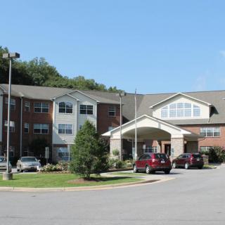 A residential building with parked cars and trees under a clear sky.