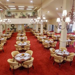 A spacious restaurant dining area with elegantly arranged tables and soft lighting from chandeliers.