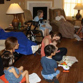 A family gathering in the living room with adults and children spending time together.