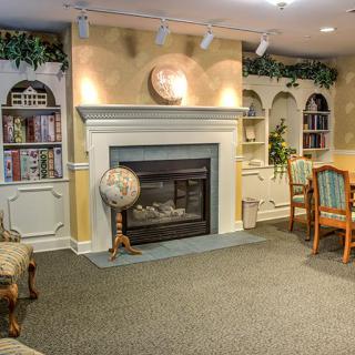Cozy library interior with a fireplace, bookshelves, globe, and seating area.