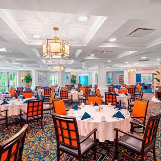 An elegant dining room with neatly arranged tables and chairs, featuring stylish decor and chandeliers.