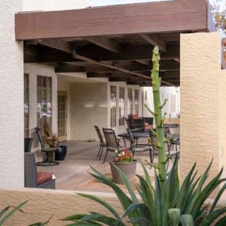 A cozy patio area with outdoor seating surrounded by desert landscaping.
