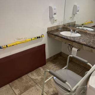 A handicap accessible bathroom with a sink, mirror, and chair.