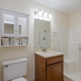 A clean and modern bathroom with a mirror, sink, toilet, and shower.