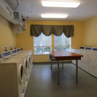 A laundry room with multiple washing machines and dryers, featuring a central folding table.