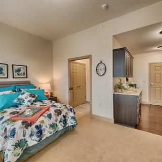 A cozy bedroom with a neatly made bed and attached kitchenette.