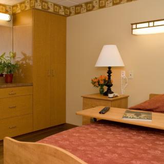 A cozy bedroom with a neatly arranged bed, wooden furniture, and soft lighting.