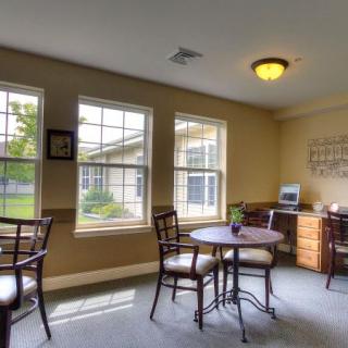 A cozy room with large windows, tables, and chairs.