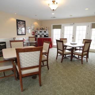 A well-lit dining area with multiple tables and chairs arranged neatly on a carpeted floor.