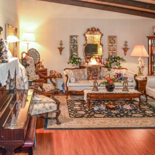 A cozy vintage-style living room with a piano, antique furniture, and warm lighting.